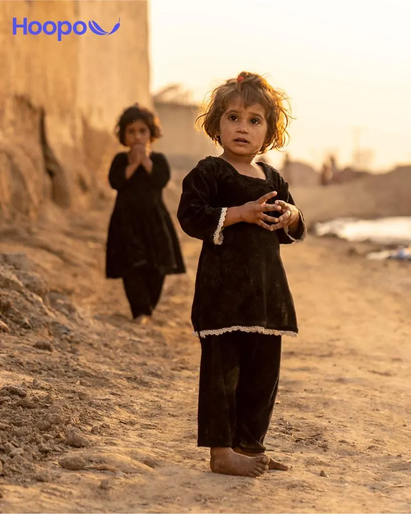 A young girl standing barefoot in a rural village